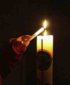 Foto Osterbotschaft – eine Kerze wird an der Osterkerze entzündet